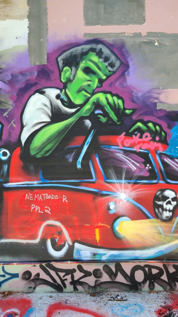 A graffiti art painting that resembles Frankenstein driving a red truck