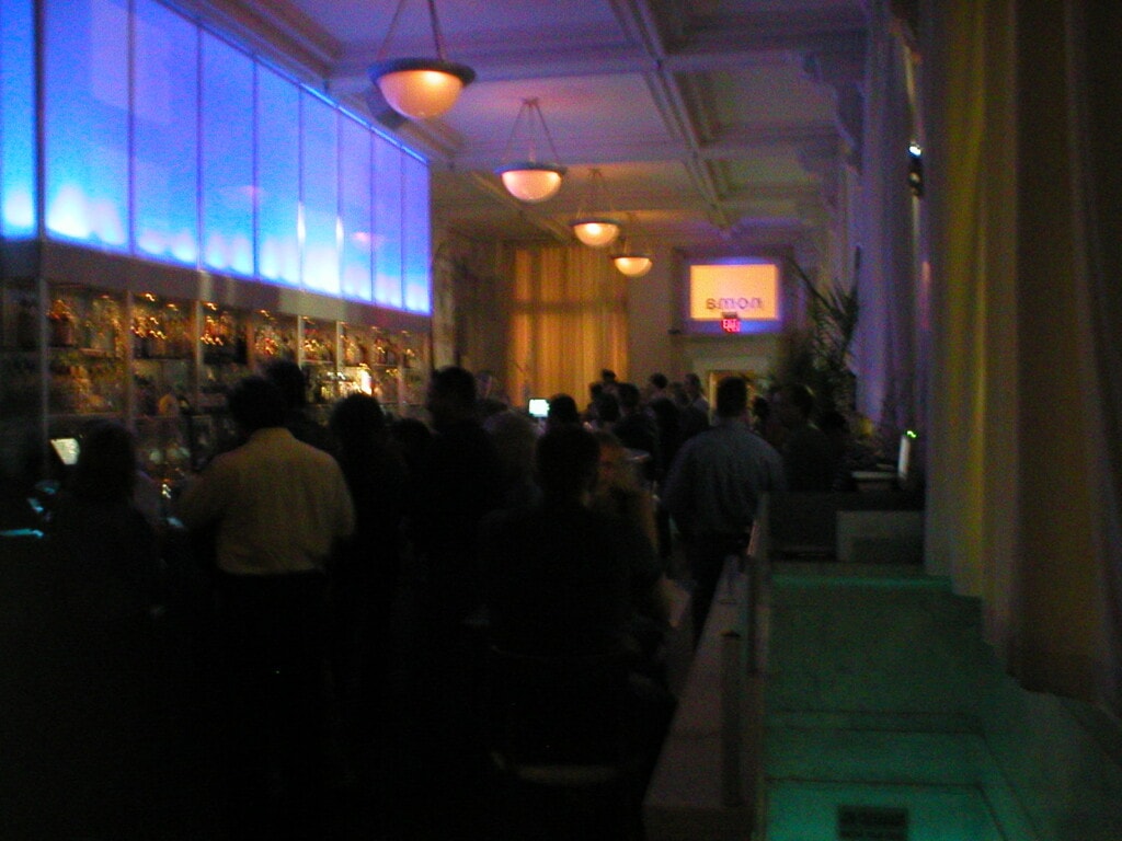 A crowded, dimly-lit lounge with blue lighting